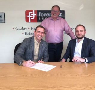 Photo of old owner signing company over to new owners