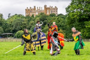 Knights fighting in the castle grounds with the castle in the background