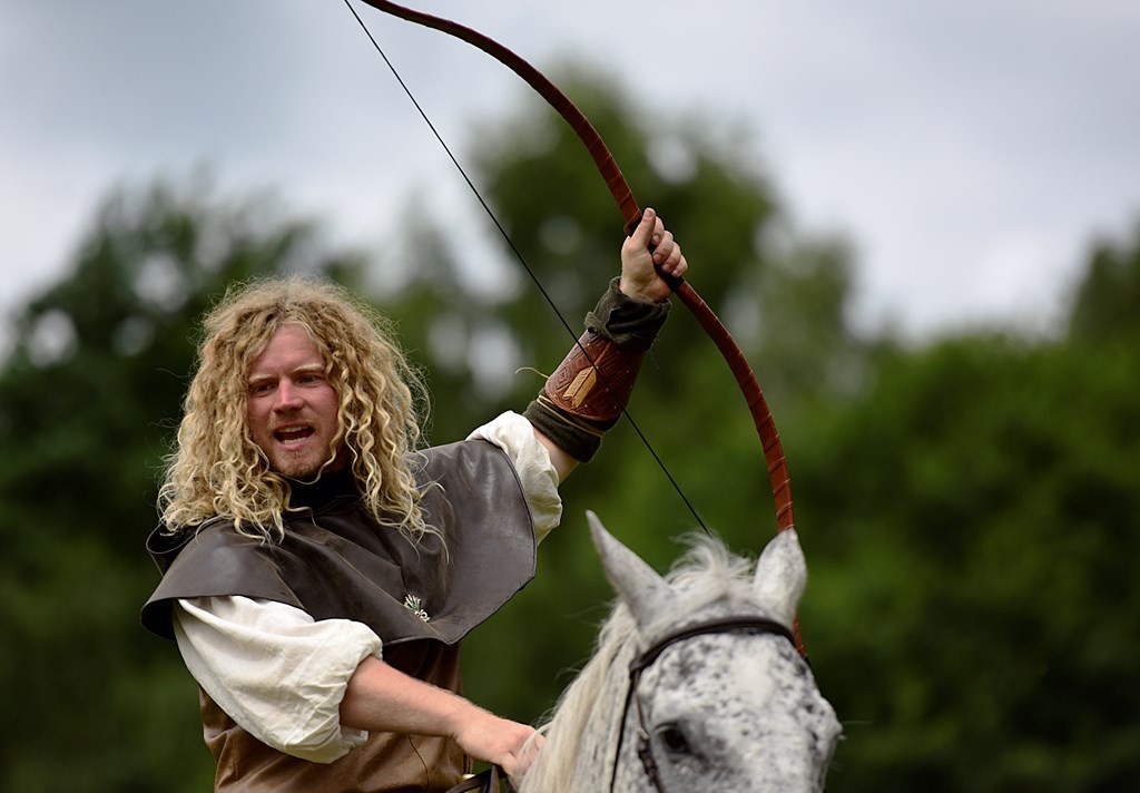 Man on horseback with a bow in hand raised up into the air