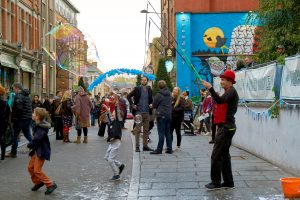 Street artist blows large bubbles on a packed broad street in Hockley