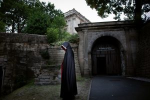 Man stood in Dark Robes, hooded. Outside the Robin Hood experience at nottingham Castle. The Castle looms in the background high up above.