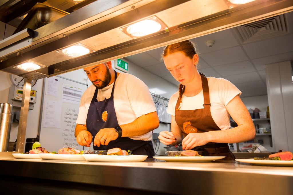 Young Chef Abigail Bunker at the pass preparing dishes to go out to the restaurant.