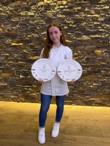 Abigail with her award win at the ceremony. The awards are two plates with things printed on them relating to the award