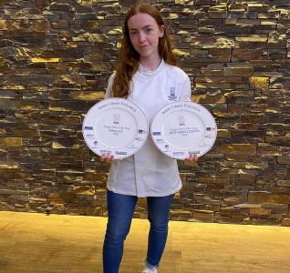 Abigail with her award win at the ceremony. The awards are two plates with things printed on them relating to the award