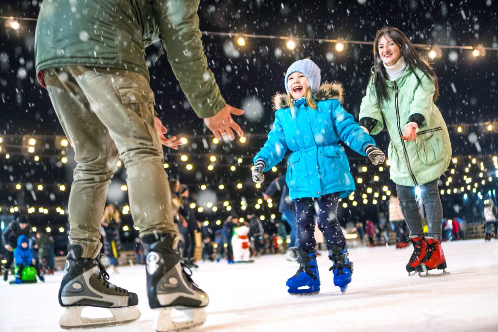 Young girl ice skating with her family at Christmas