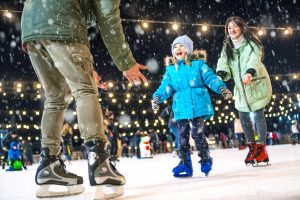 Young girl ice skating with her family at Christmas