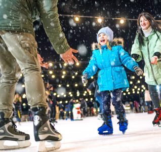 Young girl ice skating with her family at Christmas