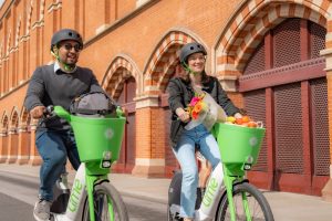 A man and a lady riding the new lime bikes which are in a lime green colour.