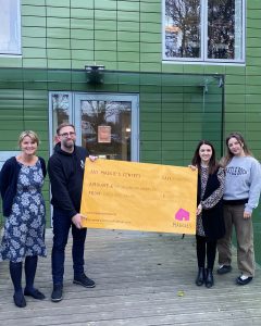 Picture of representatives from Castle Rock Brewery and Maggies outside of maggies centre with a large novelty cheque