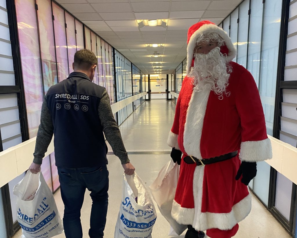 Santa at the hospital with bags of presents.