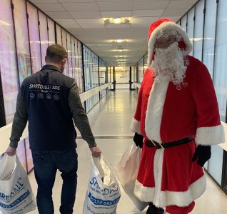 Santa at the hospital with bags of presents.