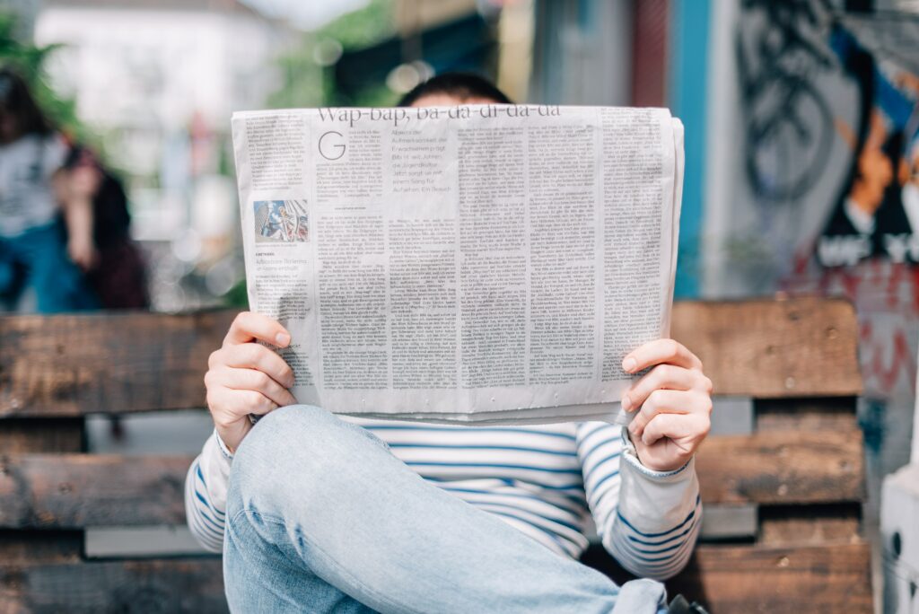 Man sat on a bench reading a newspaper