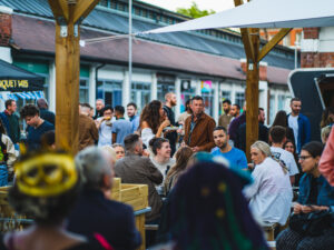 People sat around on benches at the food festival whilst its at Sneinton Market