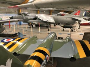 A picture of hangar two at Newark Air Museum. The photo is taken from the tail fin of a WW2 spitfire looking down the length of the plane towards the other planes in the hanger.