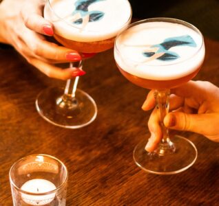 Photo of two cocktails at Cosy club with a drinkable graphic of a lady on it