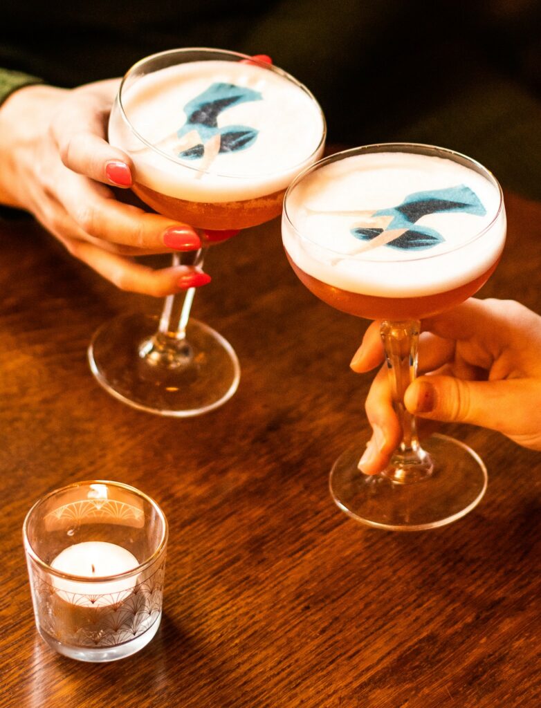 Photo of two cocktails at Cosy club with a drinkable graphic of a lady on it