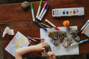 Colouring books on the table whilst a young child works on them.