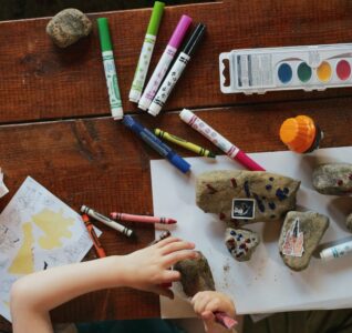 Colouring books on the table whilst a young child works on them.