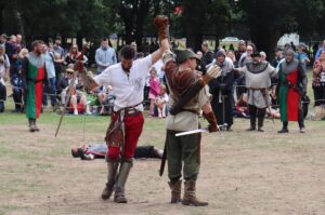 Man holding up Robin Hood's arm as he's victorious in battle at a previous Robin Hood Festival event