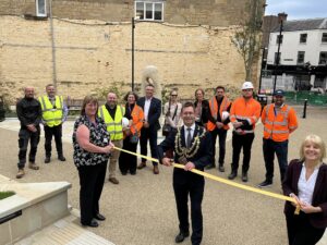 Mansfield's mayor posing for his ribbon cutting ceremony with a pair of scissors in hand and site workers in the background.