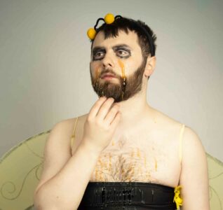 Portrait of a man dressed in a bee costume with eye makeup running down his face.