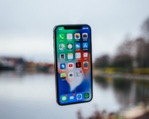 Photo of an iphone suspended in mid air with a lake in the background