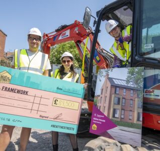 DHP Family Joseph Patten, Anwyn Williams and George Akins holding a novelty cheque next to a mobile digger