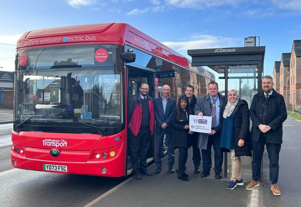 Cllr David Mellen stood with a group of people at the side of a local bus as it's pulled into a bus stop.