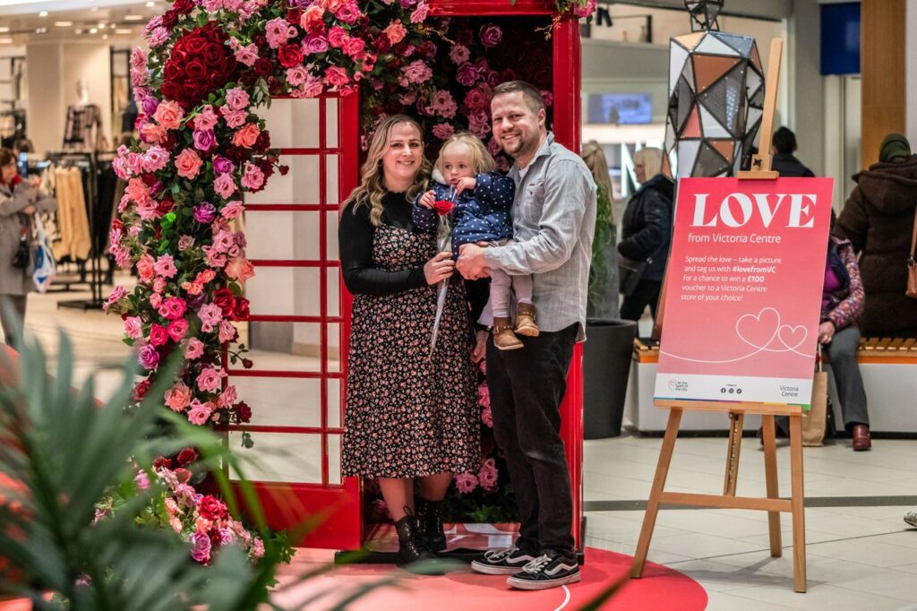 Two parents holding their child at the Victoria Centre's Valentine's Day pop up.